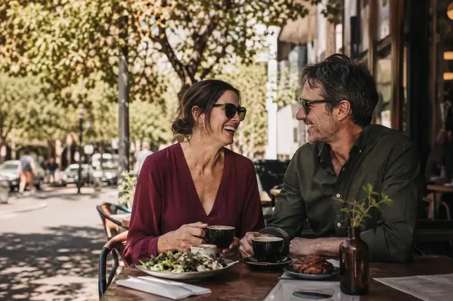 A couple laughing over brunch at a street café